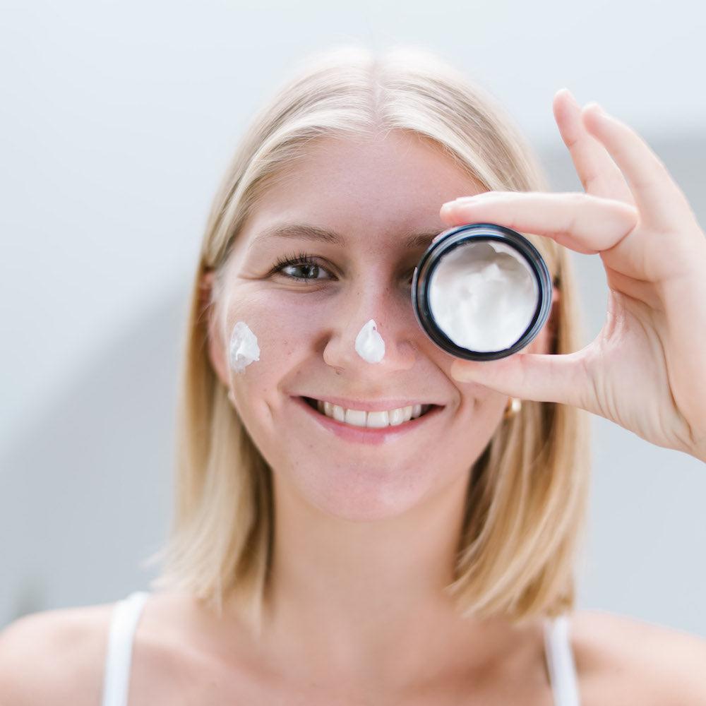 Een vrouw houdt een potje crème over haar oog - Starter Huid Set (Alle huidtypes)